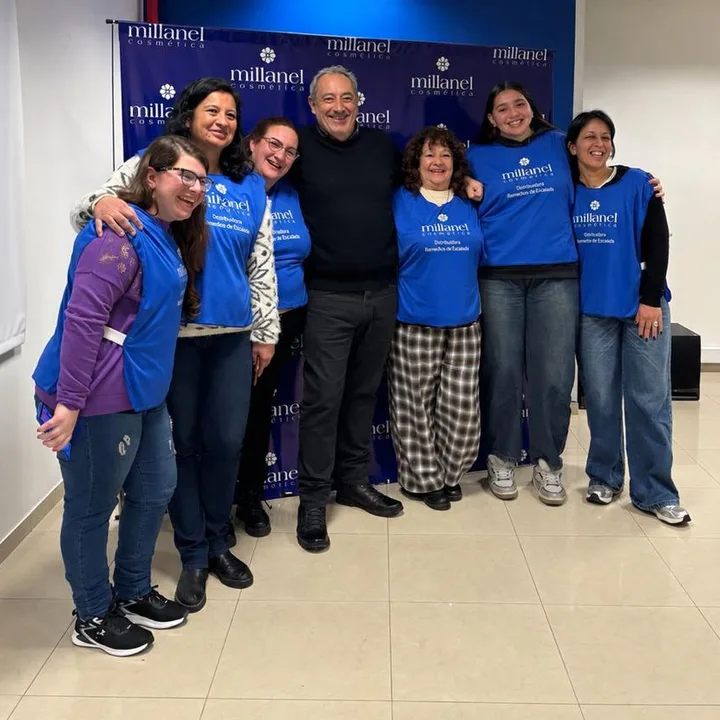 El equipo de la distribuidora abrazado frente a un cartel de Millanel