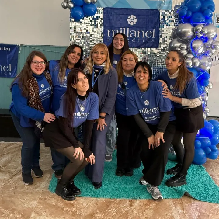Stella con su equipo, todas con la remera de la distribuidora, frente a un cartel de Millanel con globos azules
